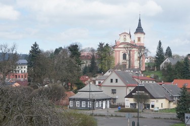 Obr. 1 – Kostel s klterem (vlevo za stromy) a opravenou budovou . 2 (zcela vlevo) nad mstem Nov Paka
