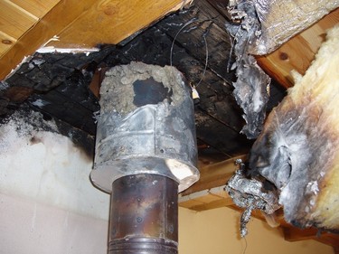 Obrázek 6 – Prostup vícevrstvého kovového komína dřevěným stropem bez průchodky. Slabá vrstva tepelné izolace a propojení komínového pláště s komínovou vložkou došlo k požáru dřevěné konstrukce stropu.