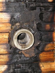 Obrázek 9 – Požár dřevěné stěny při průchodu kouřovodu do komína vedeného u fasády budovy. Místo certifikované průchodky byla použita azbestocementová trouba.