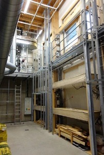 Obr. 4 Pohled do klimatické místnosti UCEEB v Buštěhradu. a) zařízení pro řízení teploty a relativní vlhkosti vzduchu, b) dlouhodobé testování poměrů při dodatečné interiérové tepelné izolaci obvodových cihelných stěn budov s dřevěnými trámovými stropy. Do horních testovacích oken se umisťují lehké konstrukční skladby (například pro dřevostavby).