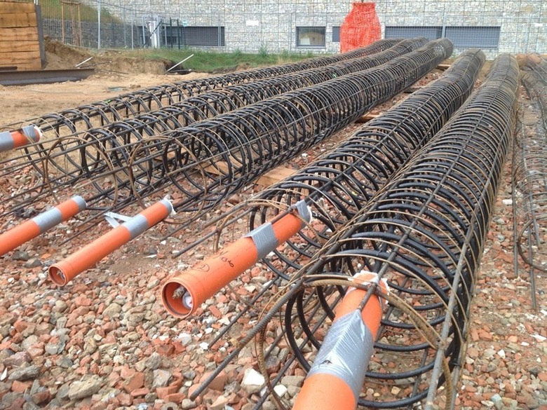 Obr.&nbsp;1 Výstužné koše vŕtaných pilót pripravené na stavenisku. Pri energetických pilótach sa do koša pred betonážou fixuje výmenník tepla (potrubie PE-Xa), takže nosný základový prvok zároveň slúži na odber a&nbsp;ukladanie tepla. Foto: GE-TRA&nbsp;s.r.o., dostupné z&nbsp;https://www.ge-tra.cz/problematiky/zemni-plosne-kolektory-energeticke-piloty