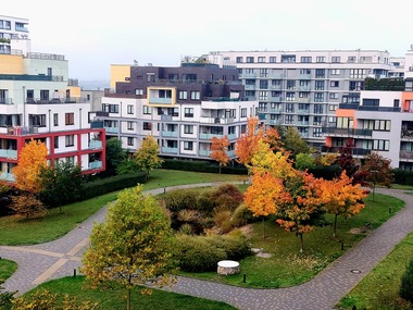 Foto&nbsp;3 Vnitroblok obytného komplexu s&nbsp;podzimní vegetací. Moderní rezidenční zástavba s&nbsp;přehledným vnitroblokem a&nbsp;udržovanou zelení. Jasně definované pěší trasy a&nbsp;otevřený prostor posilují přirozený dohled a&nbsp;pocit bezpečí.